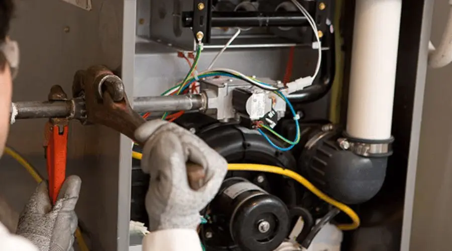 Technician using a wrench on machinery, highlighting electrical components for B & D Plumbing, Heating & A/C.