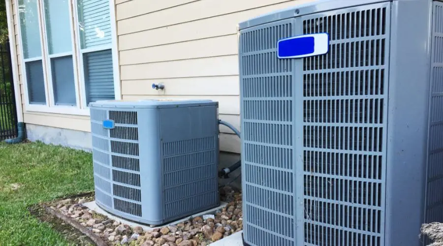 Two gray air conditioning units installed by B & D Plumbing, Heating & A/C, set against a residential building facade.
