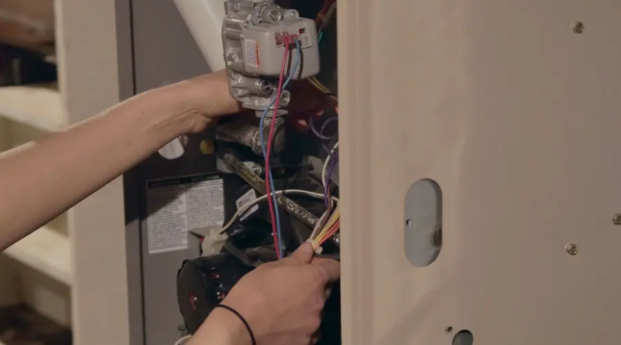 Technician servicing heater wiring for HVAC system maintenance and replacement.
