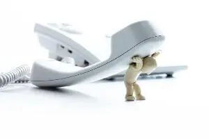 Miniature figure struggling to lift a white telephone receiver, symbolizing the importance of communication in HVAC services by B & D Plumbing, Heating & A/C.