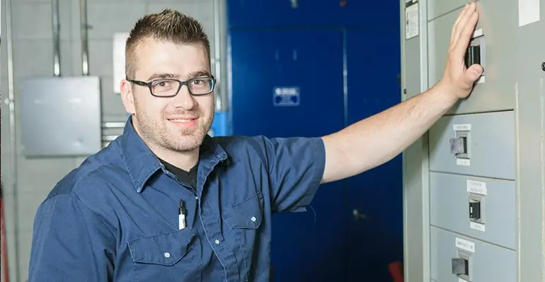 HVAC technician smiling and adjusting equipment in a service environment, representing Boutwell's Air Masters' commitment to quality HVAC repairs and installations.
