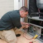 Technician on a workbench with electrical equipment, embodying HVAC expertise at Boutwell's Air Masters.