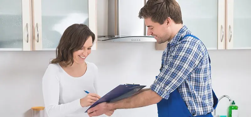 Technician discussing HVAC service details with a customer in a kitchen setting, highlighting Boutwell's Air Masters' commitment to customer service and support.