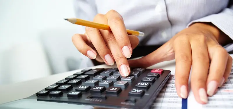 Person using a calculator with a pencil, emphasizing financial calculations and analysis in a professional setting.