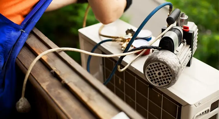 Technician servicing air conditioning unit outdoors, showcasing repair tools and equipment relevant to AC repair services in Crestview, Florida.