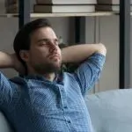 Man relaxing on a couch, illustrating comfort and peace of mind, relevant to indoor air quality and health benefits from UV air sanitizers.