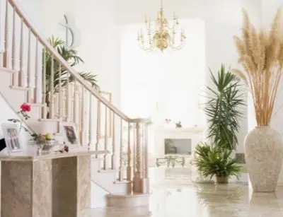 Bright, airy interior of a home featuring a staircase, elegant chandelier, and potted plants, emphasizing a comfortable living space ideal for climate control and energy efficiency.