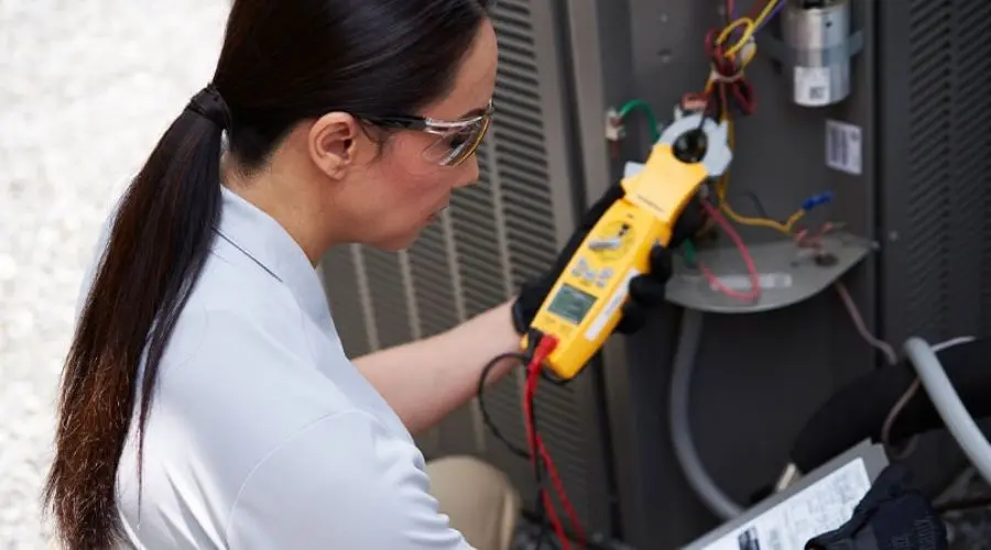 Technician using multimeter on electrical panel for HVAC diagnostics at Boutwell's Air Masters.