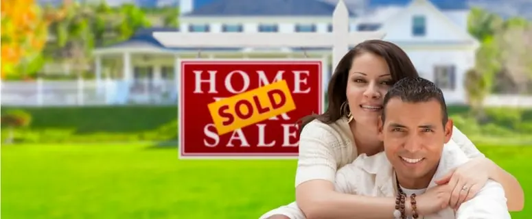 Couple celebrating home purchase in front of "Home Sold" sign, symbolizing successful real estate transaction and indoor comfort.