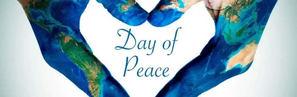 Hands painted with a world map forming a heart shape, symbolizing peace and unity on International Day of Peace.