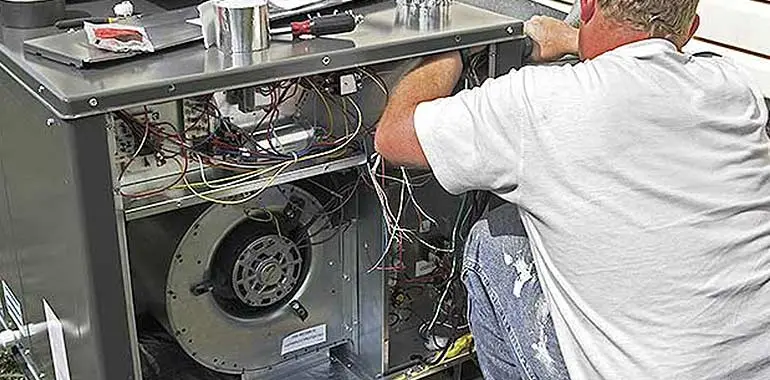 Technician repairing heating system, inspecting internal components and wiring for maintenance.