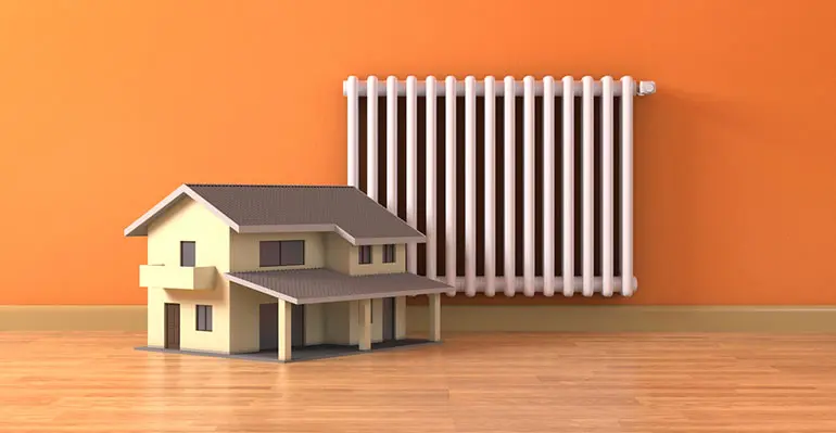 Model house beside a white radiator on an orange wall, symbolizing heating solutions and furnace services offered by Boutwell's Air Masters in Shalimar, Florida.