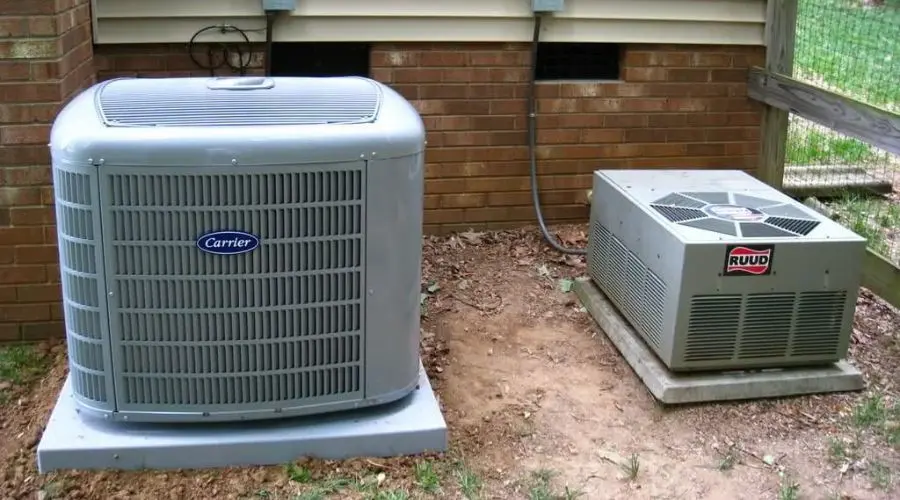 Two outdoor air conditioning units by Boutwell's Air Masters, featuring a Carrier unit and a Ruud unit on a dirt patch.