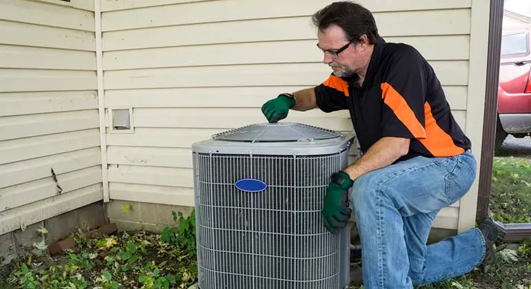 Technician performing maintenance on an outdoor air handler unit, highlighting HVAC repair services by Boutwell's Air Masters in Pensacola, Florida.