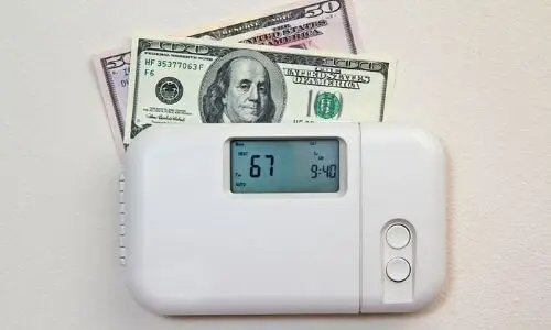 Digital thermostat displaying 67&deg;F with U.S. currency representing financial concerns and energy management.