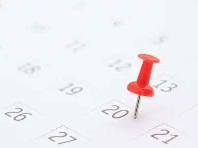 Red pushpin marking the date on a calendar, emphasizing the importance of scheduling air conditioning maintenance.