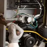 Technician repairing electronic components in HVAC systems for A-Plus Air Conditioning services.