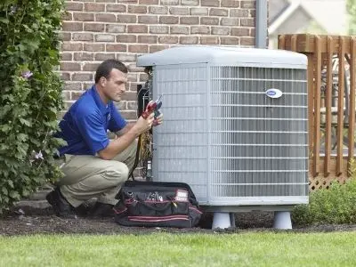 Technician performing routine maintenance on an air conditioning unit, emphasizing the importance of AC service for longevity and efficiency.