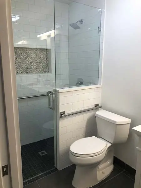 Modern bathroom featuring a walk-in shower with glass enclosure, grab bars for accessibility, and a white toilet, highlighting ADA-compliant aging-in-place renovation by A-Plus Air Conditioning & Home Solutions.