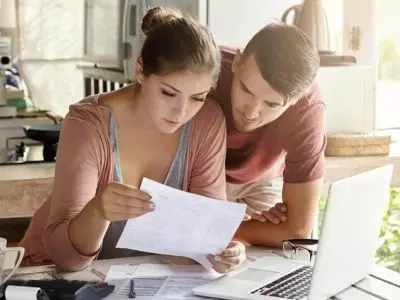 Couple reviewing documents at a table with a laptop, reflecting the importance of assessing home improvement and HVAC service options.