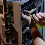 Technician repairing HVAC device with tools, focusing on internal wiring for A-Plus Air Conditioning service in Austin.