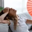 A distressed woman with long hair sitting on a couch near a window, representing home environment concerns for HVAC services.