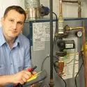 Technician repairing a boiler with tools, showcasing A-Plus Air Conditioning's heating system expertise.