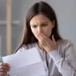 Woman with a concerned expression holding paper, representing HVAC service concerns from Atlantic Heating & Air Conditioning.