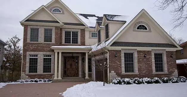 Brick house with snow-covered driveway, showcasing potential installation site for snowmelt systems by Atlantic Heating & Air Conditioning in Boston, MA.