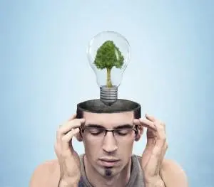 Man with glasses holding his head, featuring a light bulb with a tree inside, symbolizing eco-friendly ideas and air quality awareness.