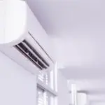Modern air conditioning unit mounted on wall in bright indoor setting with clean design and visible vents.