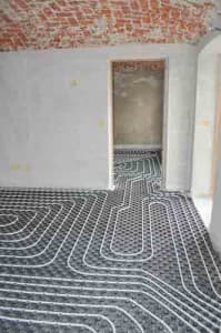 Under-the-floor radiant heating system installation with visible piping layout in a residential space, illustrating efficient heating solutions for homes.