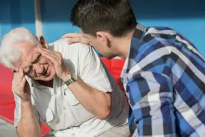 Elderly man showing signs of discomfort with a younger man offering support, emphasizing the importance of health and well-being in indoor environments.