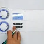 Control panel of a boiler with buttons and knobs, featuring a digital display by Atlantic Heating & Air Conditioning.