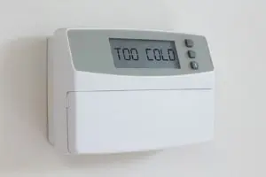 Digital thermostat displaying "TOO COLD," emphasizing HVAC system comfort management for Atlantic Heating & Air Conditioning services.