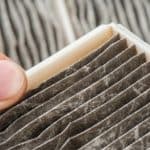 Close-up of a gray air filter showing dust accumulation, highlighting HVAC maintenance tips for eco-friendly warmth.