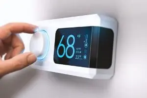 Hand adjusting a programmable thermostat displaying a temperature of 68&deg;F, symbolizing energy efficiency and climate control in HVAC systems, relevant to Atlantic Heating & Air Conditioning's focus on climate action initiatives.