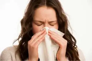 Woman holding a tissue to her nose, showing signs of respiratory discomfort, emphasizing the health risks of poor air quality and the importance of clean air ducts.