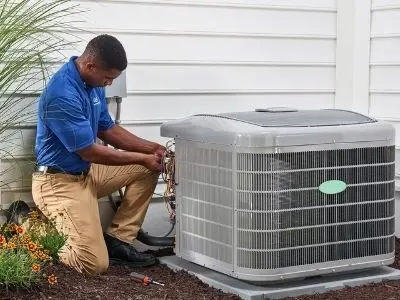 Technician performing maintenance on an outdoor air conditioning unit, emphasizing spring AC servicing and efficiency.