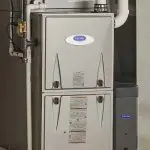 Gray metallic heating furnace unit with ventilation pipes and model specifications, vital for home heating efficiency.