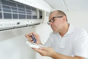 Technician inspecting and maintaining HVAC system, focusing on indoor air quality and summer preparation.