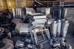 Piles of metal ductwork and HVAC components, including various shapes and sizes, essential for air handler installation and ventilation systems.