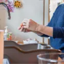 Person's hands preparing food in a cozy kitchen with a bowl of eggs and a sink, ideal for plumbing tips and home maintenance.