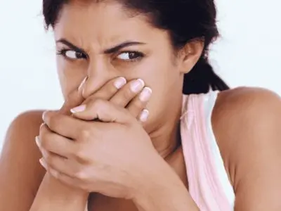 Woman covering her mouth with her hands, showing concern, possibly in response to a burning odor from an overheating furnace.