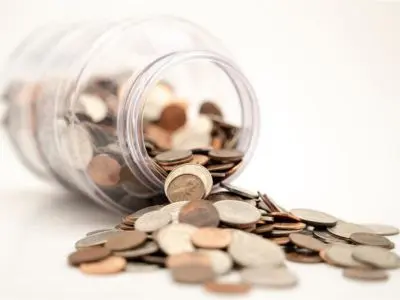 Jar of coins spilled on a surface, representing potential savings and investment in energy-efficient heat pump systems for home comfort.