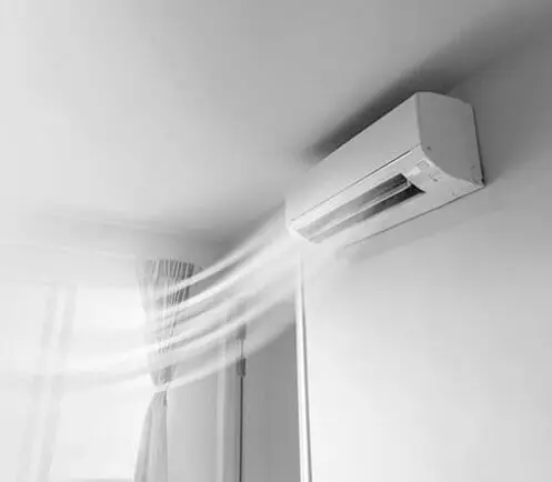 Ductless mini-split air conditioner mounted on wall with cool air flowing, illustrating efficient home climate control solutions.