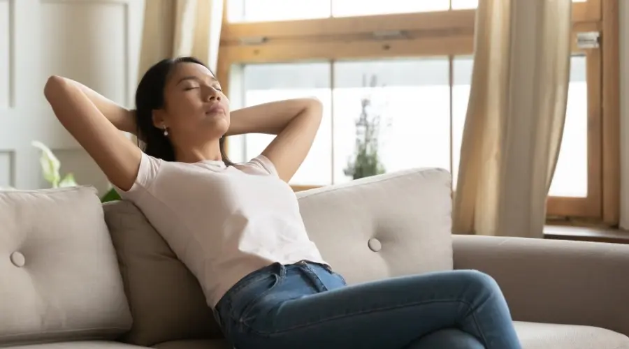 Woman relaxing on a sofa, enjoying fresh indoor air quality in a comfortable living space.