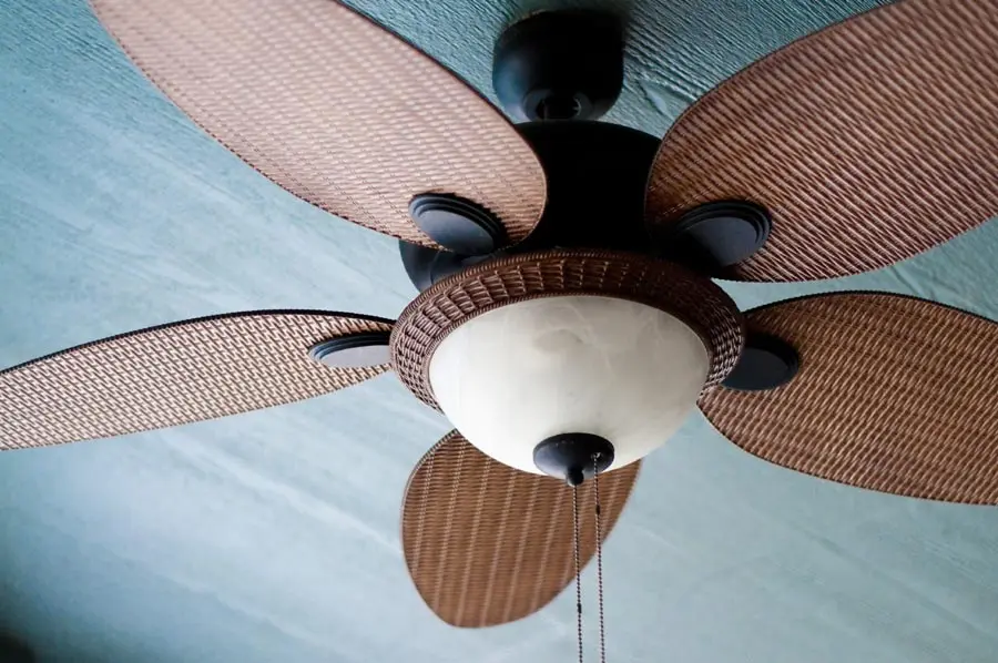 Ceiling fan with woven blades and light fixture, illustrating an effective cooling solution for homes in hot weather, as discussed in the blog post on alternatives to air conditioning.