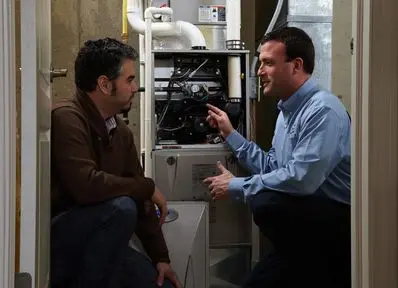 Two technicians discussing furnace maintenance in a residential setting, highlighting North Point Air Conditioning & Heating's expertise in heating services.