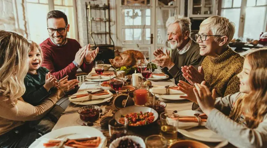 Diverse group enjoying a festive meal around a beautifully set table, showcasing family togetherness and celebration.